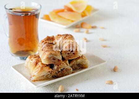 Türkisches Baklava-Dessert mit Nuss, Erdnüssen, Honigsirup mit schwarzem Tee und getrockneten Früchten, getrockneten Aprikosen und Mango. Mittelöstliche oder arabische Gerichte. Stockfoto