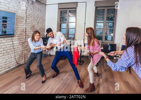 Geschäftsleute ziehen im Büro an Seil, lustige Teambuilding-Aktivitäten. Stockfoto