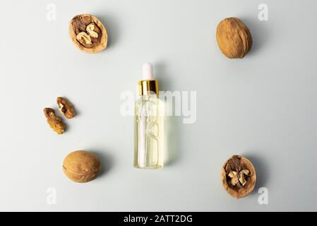 Kosmetik- und Heilöl aus Nussbaum auf blauem Pastellgrund. Nussbaum kosmetisches Feuchtigkeitsspendende Serum. Das Konzept der natürlichen Inhaltsstoffe in der Kosmetik. Stockfoto