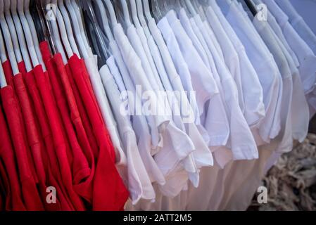 Rot-weiße Casual-T-Shirts auf einem Kleiderbügel zum Verkauf vor einem Bekleidungsgeschäft. Stockfoto