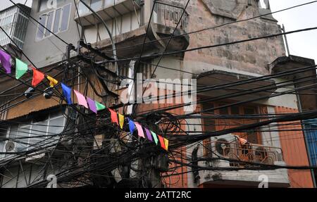 Unordentliche verschlungene Elektrizität, Telekommunikationsleitungen, Kabel an Polen in Hanoi, Vietnam Stockfoto