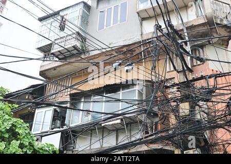 Unordentliche verschlungene Elektrizität, Telekommunikationsleitungen, Kabel an Polen in Hanoi, Vietnam Stockfoto