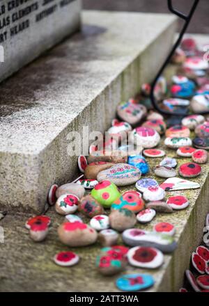 Bemalte Felsen mit Poppy-Blumen, die auf dem Kriegsdenkmal in Appledore, Nord-Devon, England, Großbritannien, gelegt wurden Stockfoto