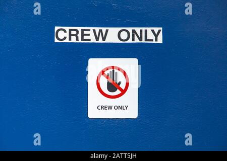 Schwarzes Schild auf blauem Hintergrund, das nur Die Crew sagt. Warnschild auf der Kommandobrücke einer Passagierfähre, die in einem kanadischen See navigiert. Stockfoto