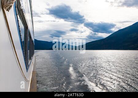 Lehnen Sie sich vom Deck eines Fährschiffs in einem kanadischen See ab. Blick zurück auf den Abfahrtsort und nach dem aufwachen des Bootes im Wasser. Stockfoto