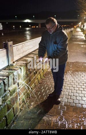 Zell, Deutschland. Februar 2020. Ortsbewohner Eberhard filet mit seinem Handy eine Stelle an der Hochwasserschutzwand in Zell (Rheinland-Pfalz), wo das Moselwasser in die Mauer eindringt. Wird die Mauer überschwemmt, stehen Teile der Stadt unter Wasser. Credit: Thomas Frey / dpa / Alamy Live News Stockfoto