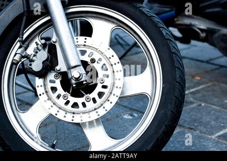Nahaufnahme des Vorderrads eines Rennmotorrads. Dies sind Bremssattel, Rotor, Felge, Reifen und Federung. Nahaufnahme. Stockfoto