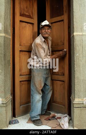 Umweltporträt eines älteren Tischlers bei der Arbeit, Holztür manuell schleifen. Alltag in Antigua, Guatemala. Januar 2019 Stockfoto