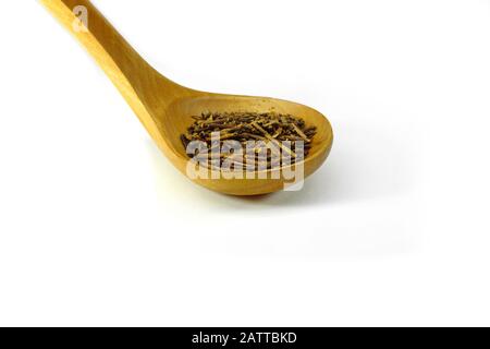 Grüner japanischer Kukicha-Tee (Twig oder Stiel oder Stick), der bei makrobiotischer Ernährung beliebt ist. Kukicha auf einem Holzlöffel. Stockfoto