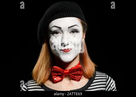 Süßer weiblicher MIME auf Schwarz. MIME-Schauspielerin, gekleidet mit gestreiftem T-Shirt Stockfoto