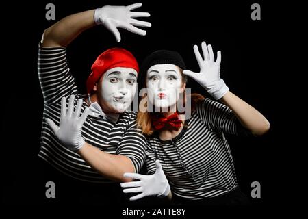 Zwei Mimes lehnen sich an imaginäre Wand mit Händen in weißen Handschuhen Stockfoto