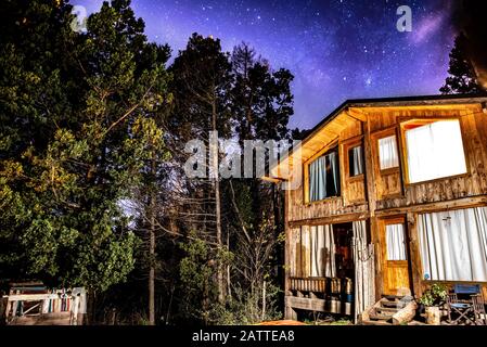 Bariloche, ARGENTINIEN, 19. JUNI 2019: Außenansicht einer gemütlichen und entspannenden Holzhütte im Wald mit einem wundervollen Sternenhimmel Stockfoto