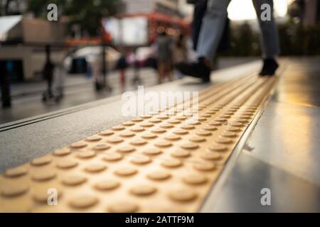 Fußgänger zu Fuß auf taktilen Pflaster auf Fußpfad Stockfoto