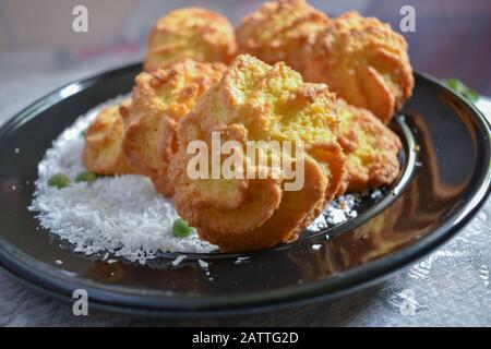 Ein Teller mit frischen, köstlichen Kokosmakronen auf einem schwarzen Teller, der in einem Winkel gedreht wurde Stockfoto