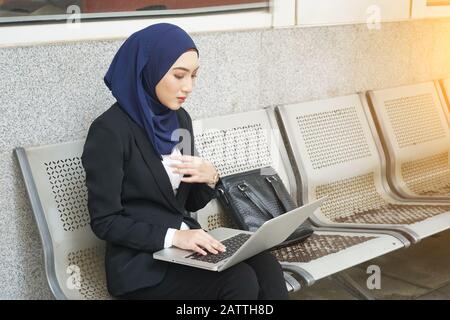 Attraktive muslimische Frau auf einem Laptop und Telefon Stockfoto