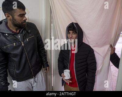 11. Dezember 2019 in Sarajevo, Bosnien und Herzegowina: Männer, die sich im Flüchtlingslager Usivak in der Nähe von Sarajevo entspannen.In Bosnien und Herzegowina versuchen rund 8000 Flüchtlinge und Migranten, einen Weg zu finden, wie sie die Grenze nach Kroatien überschreiten und weiter in die westeuropäischen Länder kommen. Einige von ihnen leben in überfüllten Flüchtlingslagern, einige von ihnen bedrängen verlassene Gebäude oder schlafen einfach auf den Straßen. Viele von ihnen berichten, dass, wenn sie von der kroatischen Polizei an der Grenze gefangen werden, sie geschlagen werden, ihr Bargeld, Smartphones und Wertgegenstände gestohlen werden, Jacken und Schuhe verbrannt werden und sie vom Bo geschlagen werden Stockfoto