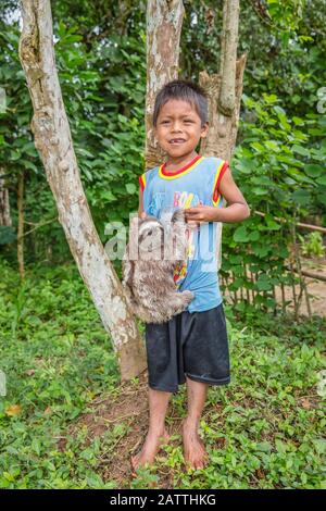 Kleiner Junge mit seinem "Haustier"-Braunfaultier, Bradypus variegatus, San Francisco Village, Loreto, Peru, Südamerika Stockfoto