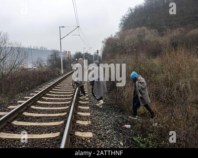 Dezember 2019 in Sarajevo, Bosnien und Herzegowina: Drei Migranten, die durch die Eisenbahnlinien in der Nähe von Sarajevo laufen.In Bosnien und Herzegowina versuchen rund 8000 Flüchtlinge und Migranten, einen Weg zu finden, wie sie die Grenze nach Kroatien überqueren und weiter in die westeuropäischen Länder kommen. Einige von ihnen leben in überfüllten Flüchtlingslagern, einige von ihnen bedrängen verlassene Gebäude oder schlafen einfach auf den Straßen. Viele von ihnen berichten, dass, wenn sie von der kroatischen Polizei an der Grenze gefangen werden, sie geschlagen werden, ihr Geldmittel, Smartphones und Wertgegenstände gestohlen werden, Jacken und Schuhe verbrannt werden und sie sind Stockfoto