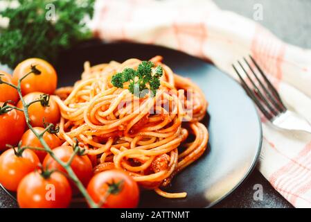 Spaghetti italienische Pasta auf schwarzem Teller mit Tomaten und Petersilie im Restaurant italienisches Speise- und Menükonzept / Spaghetti-Bolognese Stockfoto