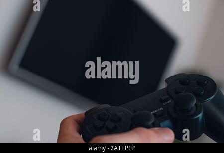 Junger Spieler, halten Sie sich in der Spielkonsole und im Fernsehen in Richtung ihn. POV-Aufnahmen. Spielkonzept Stockfoto