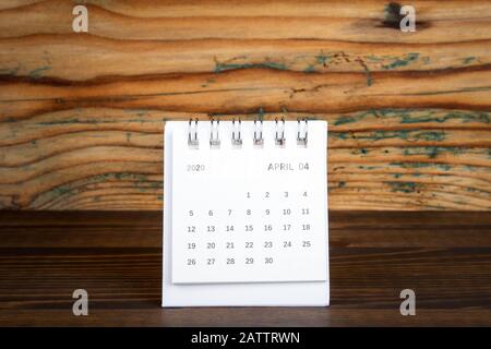 2020 April. Weißer Papierkalender auf einem Holztisch. Zeitplanung, Tageszählung und Feiertage Stockfoto