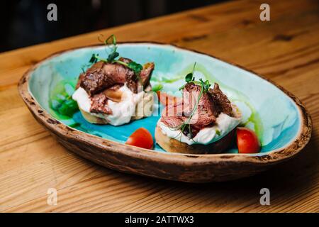 Bruschetta mit Roastbeef auf Zwiebel Brot medium gebratenes Roastbeef und saurer Sahne-Sauce. Leckere Snacks, Sandwiches. Stockfoto