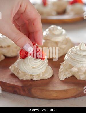 Der Prozess der Herstellung von Pavlova Dessert, die Dekoration der Meringue mit Erdbeeren Stockfoto