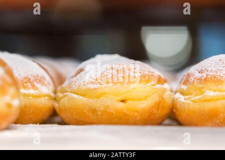 Seitenansicht auf Donuts mit pulverförmigtem Zucker oben. Österreichische Traditionsbäckerei, auch Krapfen (z. B. in Bayern oder Österreich) oder Berliner genannt. Stockfoto