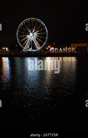 Blick auf die Stadt bei Nacht mit Lichtern auf dem Wasser, Riesenrad Stockfoto