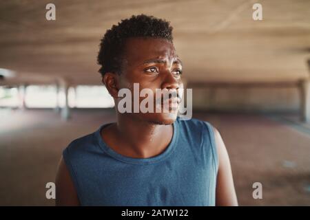 Portrait eines müden afroamerikanischen jungen, sportlichen Mannes, der nach dem Workout im Freien schwitzt und wegschaut Stockfoto