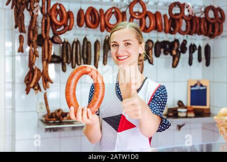 Frau, die Würstchen verkauft, die mit den Daumen nach oben schreibt Stockfoto