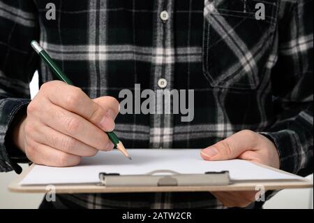 Nahaufnahme der Hand eines Mannes, der ein Dokument mit einer Zwischenablage signiert Stockfoto