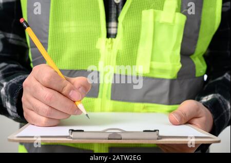 Nahaufnahme der Hand eines Mannes, der ein Dokument mit einer Zwischenablage signiert Stockfoto