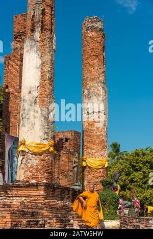 Ayutthaya, Thailand - 1. Januar 2016: Buddhistischer Mönch in orangefarbenem Gewand mit den Tempelruinen Wat Thammikarat im Hintergrund Stockfoto