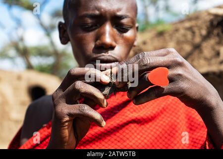 Serengeti, TANSANIA - 7. Januar: Afrikanischer Mann hält einen schwelenden Kuchen in den Händen mit einem roten Herzring. Tansania, Afrika. Stockfoto