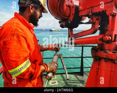 Die Crew der Marine plant Wartungen und Schmierfette auf dem FIFI-Brandbekämpfungsmonitor an Bord eines Schiffes Stockfoto