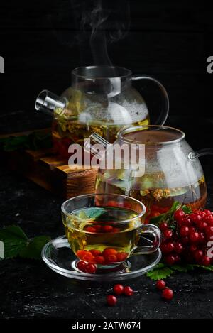 Tee aus Viburnum und Waldkräutern. Heiße Wintergetränke. Auf schwarzem Hintergrund. Draufsicht. Stockfoto