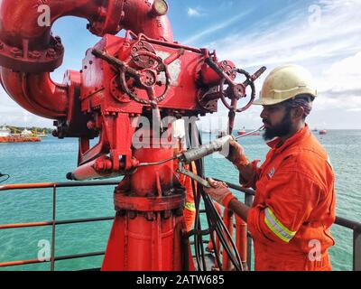 Die Crew der Marine plant Wartungen und Schmierfette auf dem FIFI-Brandbekämpfungsmonitor an Bord eines Schiffes Stockfoto