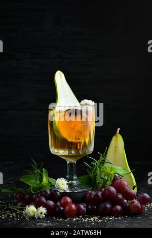 Heiße Wintergetränke. Heißer Weißwein mit Birne und Zimt. Im Glas. Draufsicht. Auf schwarzem Hintergrund. Stockfoto