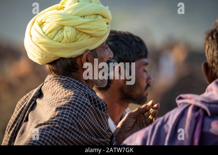 Pushkar, Rajashtan /Indien - 07/11/2019. Indischer Alter Mann, Der in gelbem Turban raucht, in Menschenmenge Stockfoto