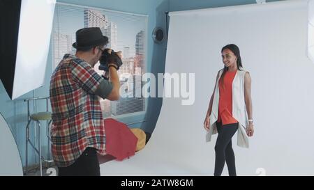 Backstage von Fotoshooting: Multirassische junge Frau posiert für Modemagazin Fotoshooting. Hinter dem Modell befindet sich ein weißer Hintergrund. Stockfoto