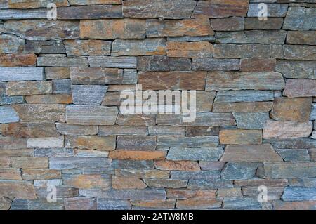 Hintergrund der Steinschichten. Natursteinmauer, Bautextur mit Zaun. Hintergrund Stockfoto