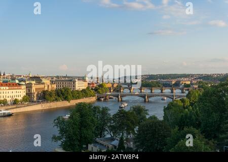 Panoramablick auf den Fluss Vltava mit Karlsbrücke und historischen Türmen bei Sonnenuntergang Stockfoto