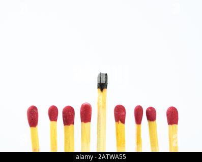 Acht neue Match-Sticks mit einem verwendeten Match, das in einer Linie ausgerichtet und über einem weißen Hintergrund isoliert ist Stockfoto