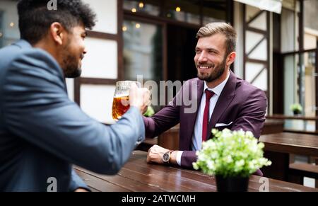 Einen Pint mit einem Freund haben. Fröhliche junge Männer toben mit Bier, während sie an der Bar zusammen sitzen Stockfoto