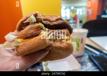 Eine Person, die einen Big Mac Hamburger in einem McDonalds Fast-Food-Restaurant isst. Stockfoto
