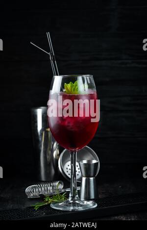 Flamingo-Cocktail. Spirituosen, Brombeeren und Minze. Alkoholischer Cocktail im Glas. Auf Holzgrund. Draufsicht. Freier Speicherplatz. Stockfoto