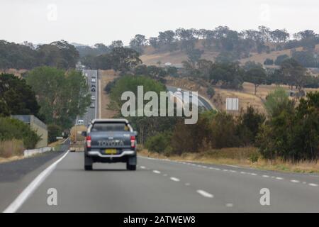 Autos, die auf einem großen Bad auf einer Autobahn durch den australischen Busch auf dem hume Highway fahren Stockfoto