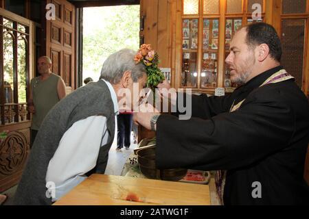 Christian Priest gibt den Menschen das Kreuz zu küssen und segnet sie mit heiligem Wasser an einem großen Kirchenurlaub in Sofia, Bulgarien am 6. Mai 2012. Stockfoto