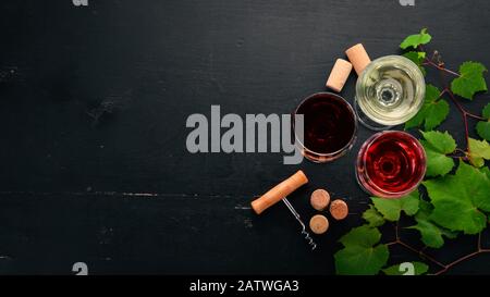 Roter und weißer Wein in der Brille. Trauben. Auf schwarzem Holzhintergrund. Freier Speicherplatz für Text. Draufsicht. Stockfoto